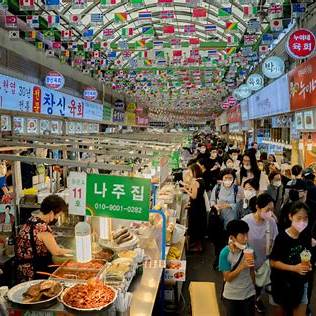 Korea Food Travel Guide 2025 busy food alley inside Gwangjang Market in Seoul filled with tourists and vendors