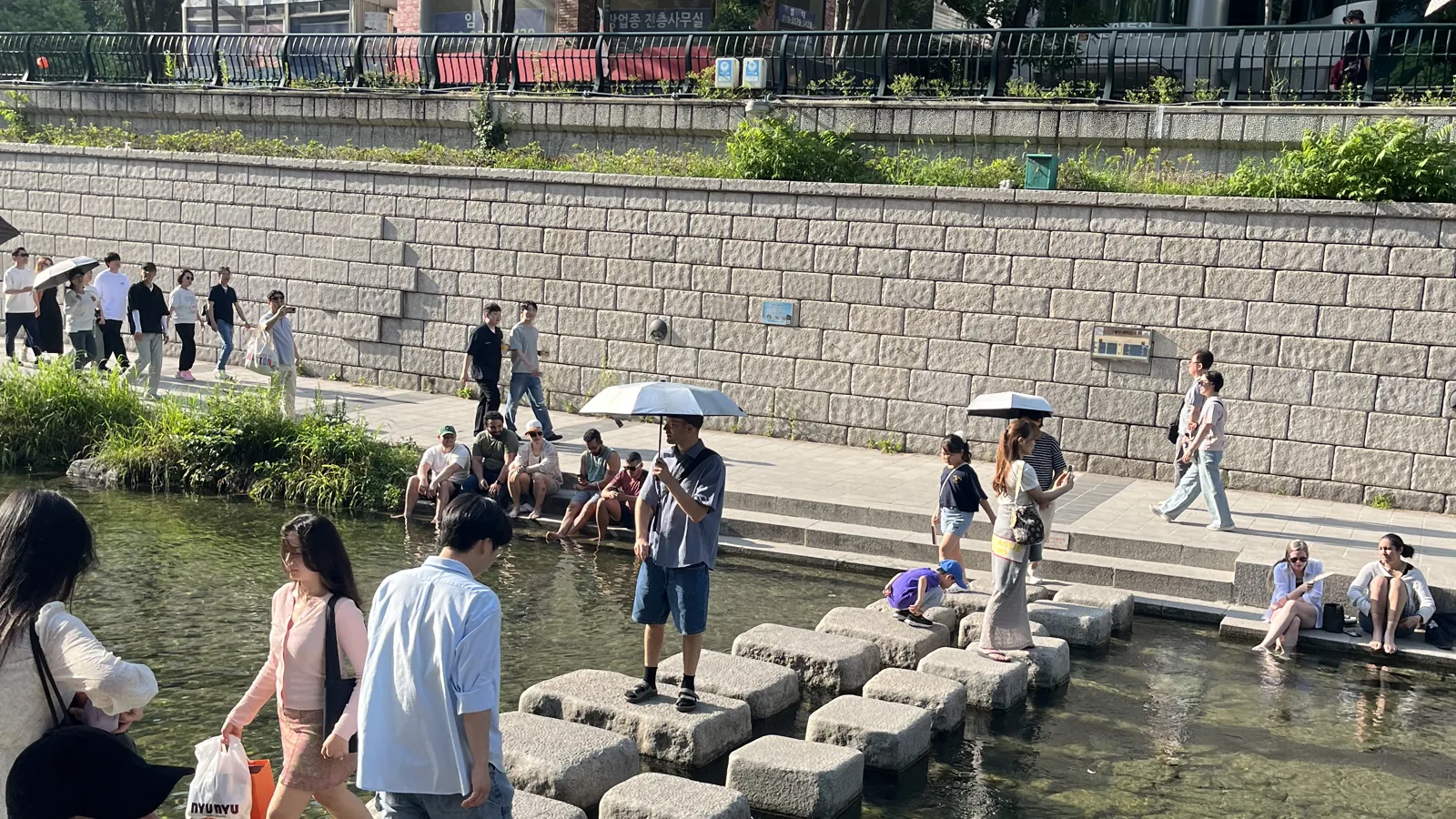 Cheonggyecheon in summer with people at the stepping stones below the stone banks