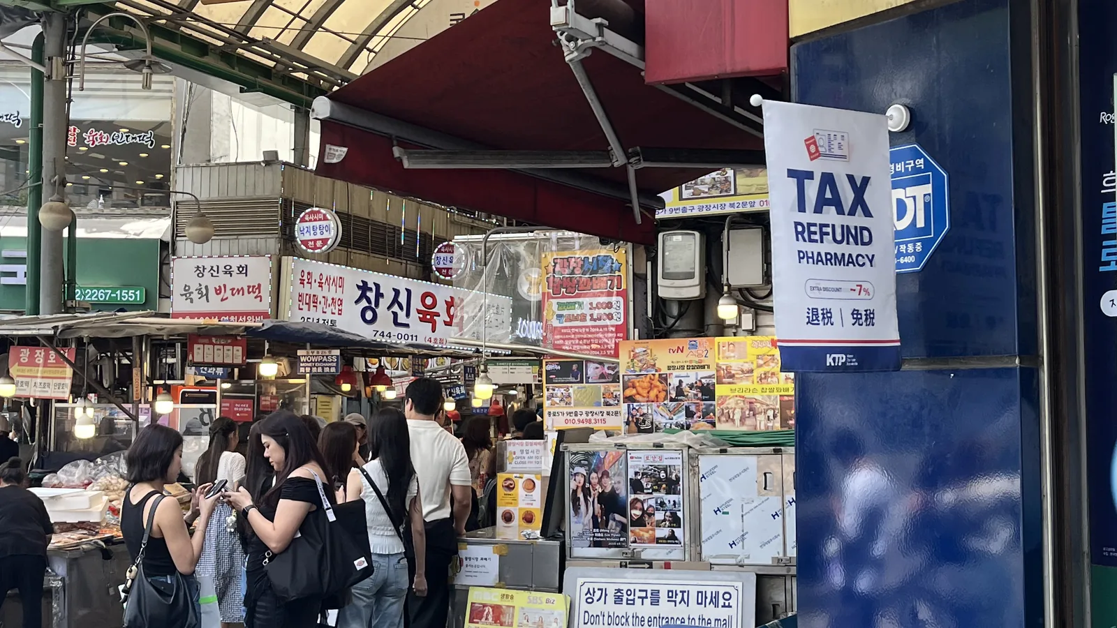 How to visit Gwangjang Market shown by a market entrance and crowds