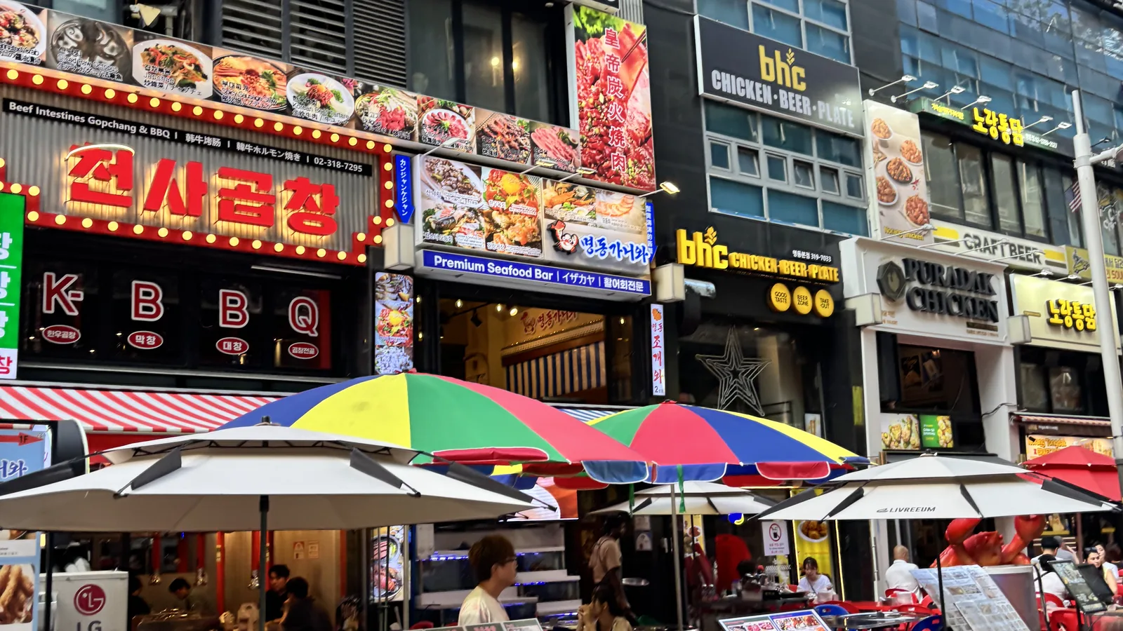 best restaurants in Myeongdong along a busy restaurant street with grill and chicken signboards