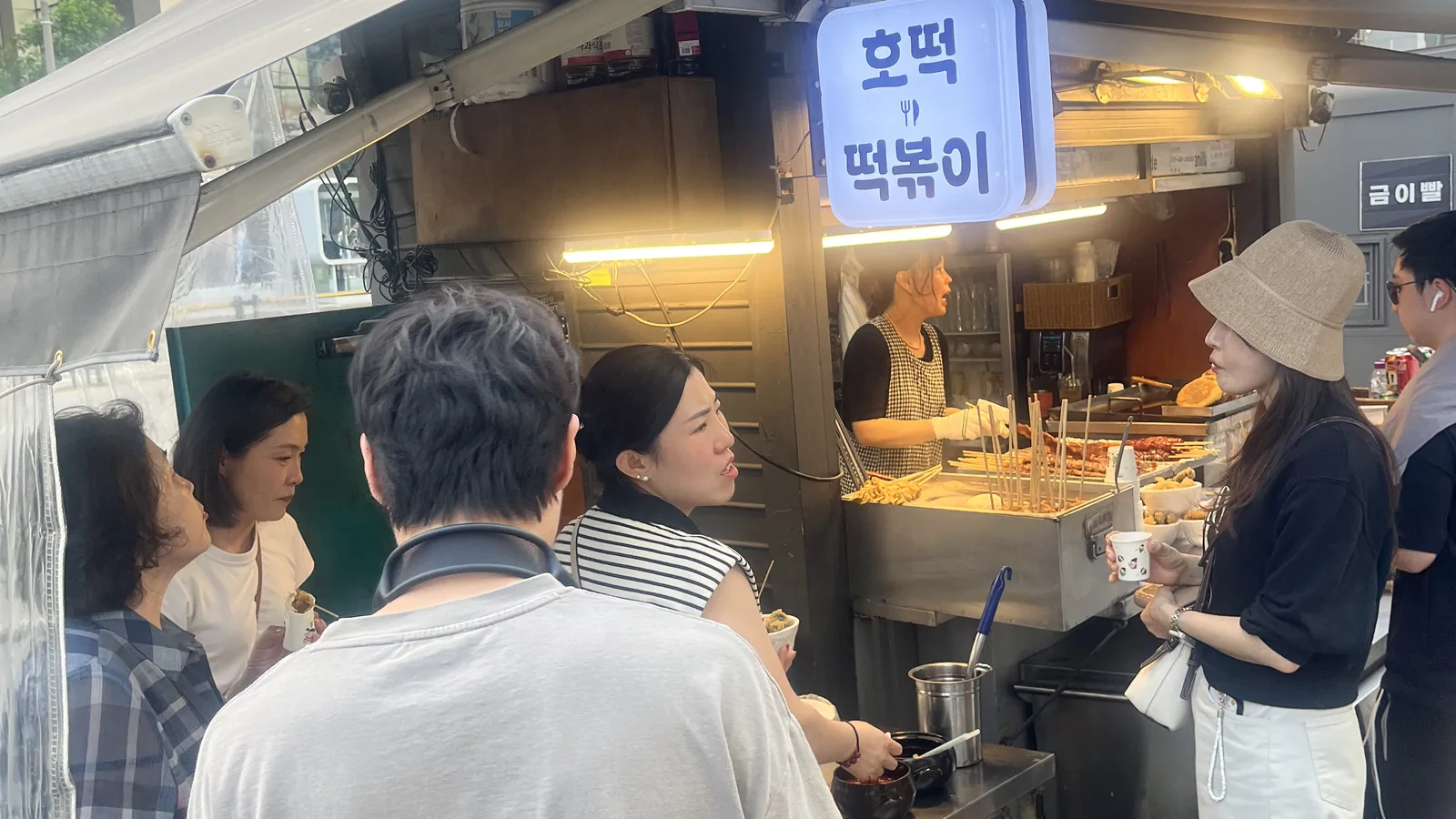 Myeongdong street food stall serving hotteok and tteokbokki on a busy evening