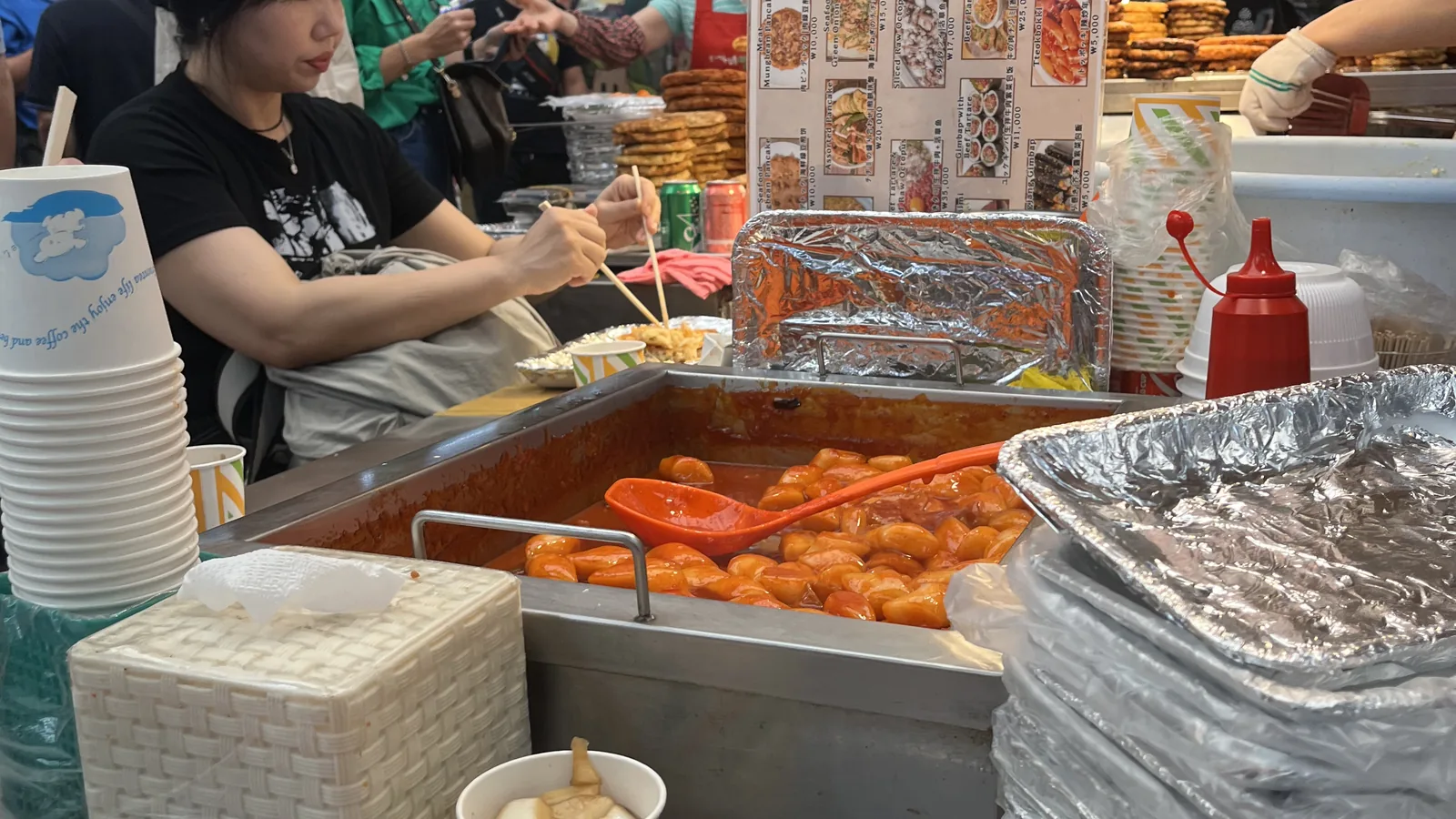 What to eat at Gwangjang Market shown by a tteokbokki and fried food stall