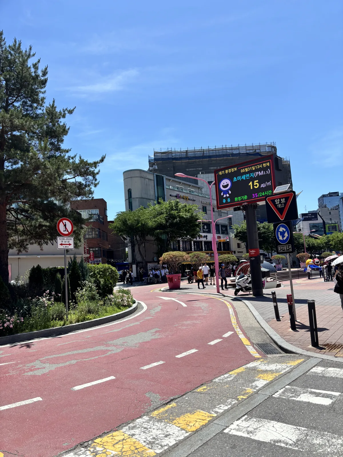 Quiet red-paved walking street in Hongdae during the day with green trees