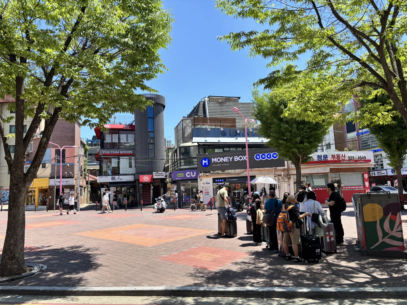 People strolling a sunlit street in Hongdae during the day in Seoul