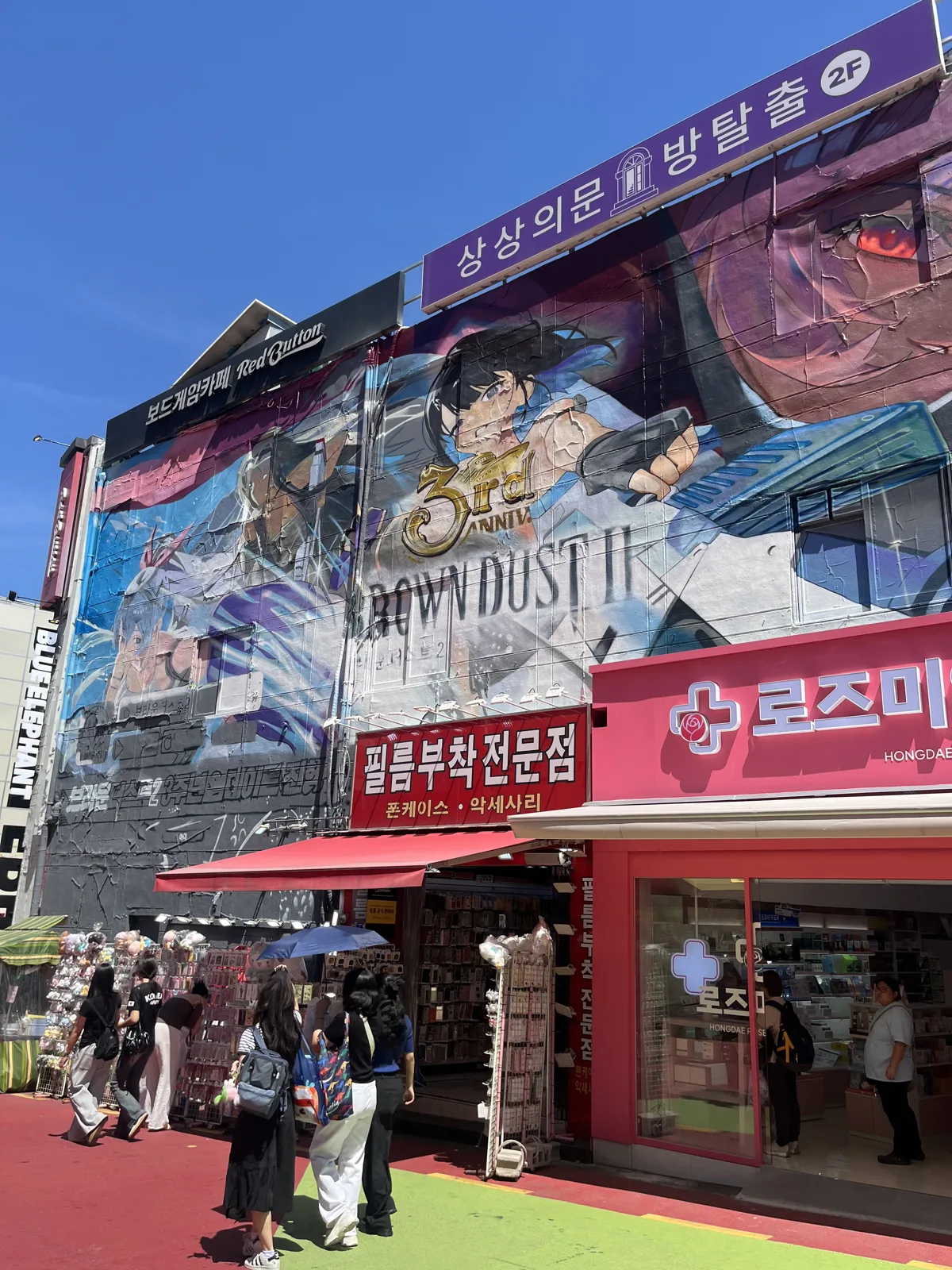 Mural-covered building on the Hongdae shopping street with shops and an escape-room cafe
