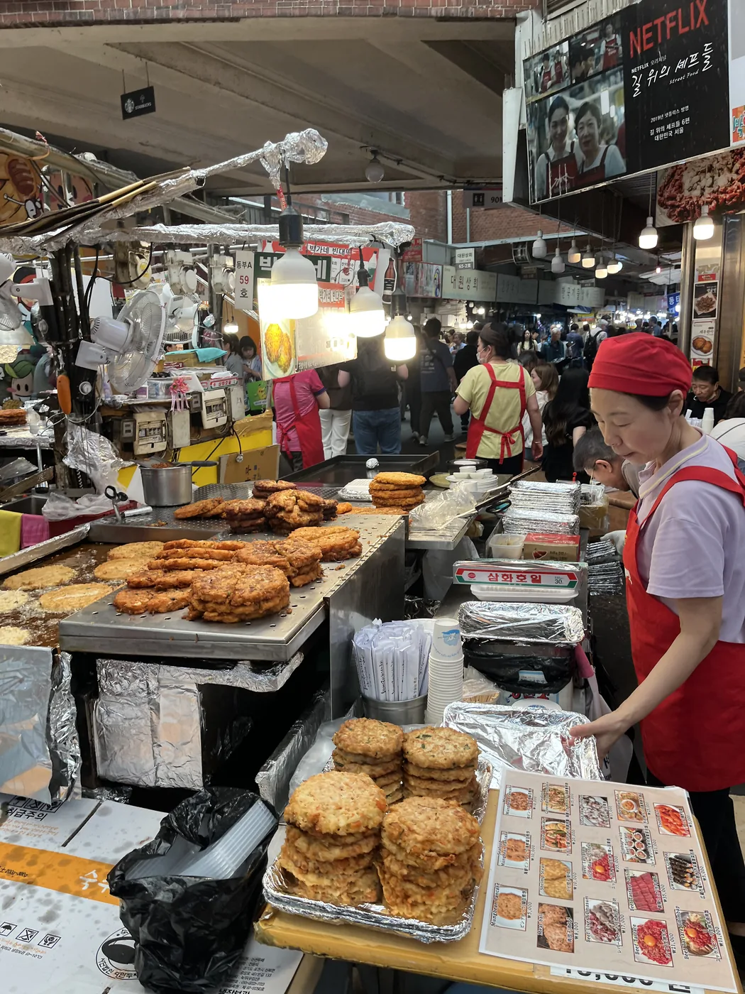 Gwangjang Market food guide view of a vendor frying bindaetteok mung bean pancakes