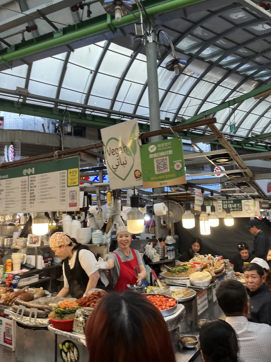 How to visit Gwangjang Market shown by a covered market arcade full of stalls