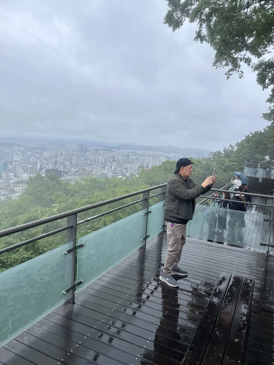 N Seoul Tower observatory view of a visitor at the glass-railed terrace below the tower