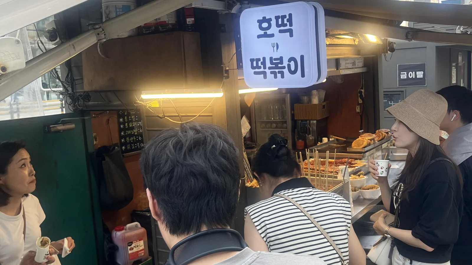 Myeongdong street food crowd gathered around a hotteok and tteokbokki stall