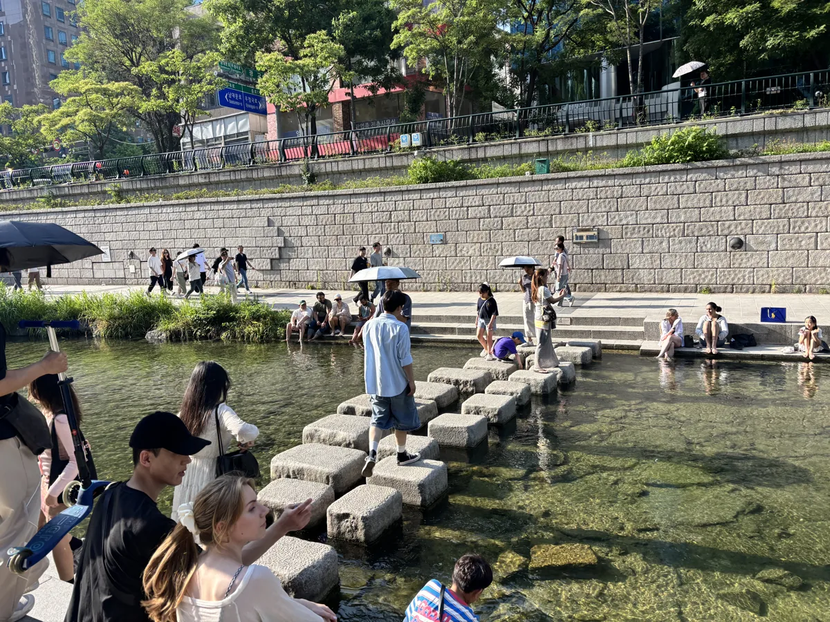 Cheonggyecheon in summer with people crossing the stepping stones over the stream