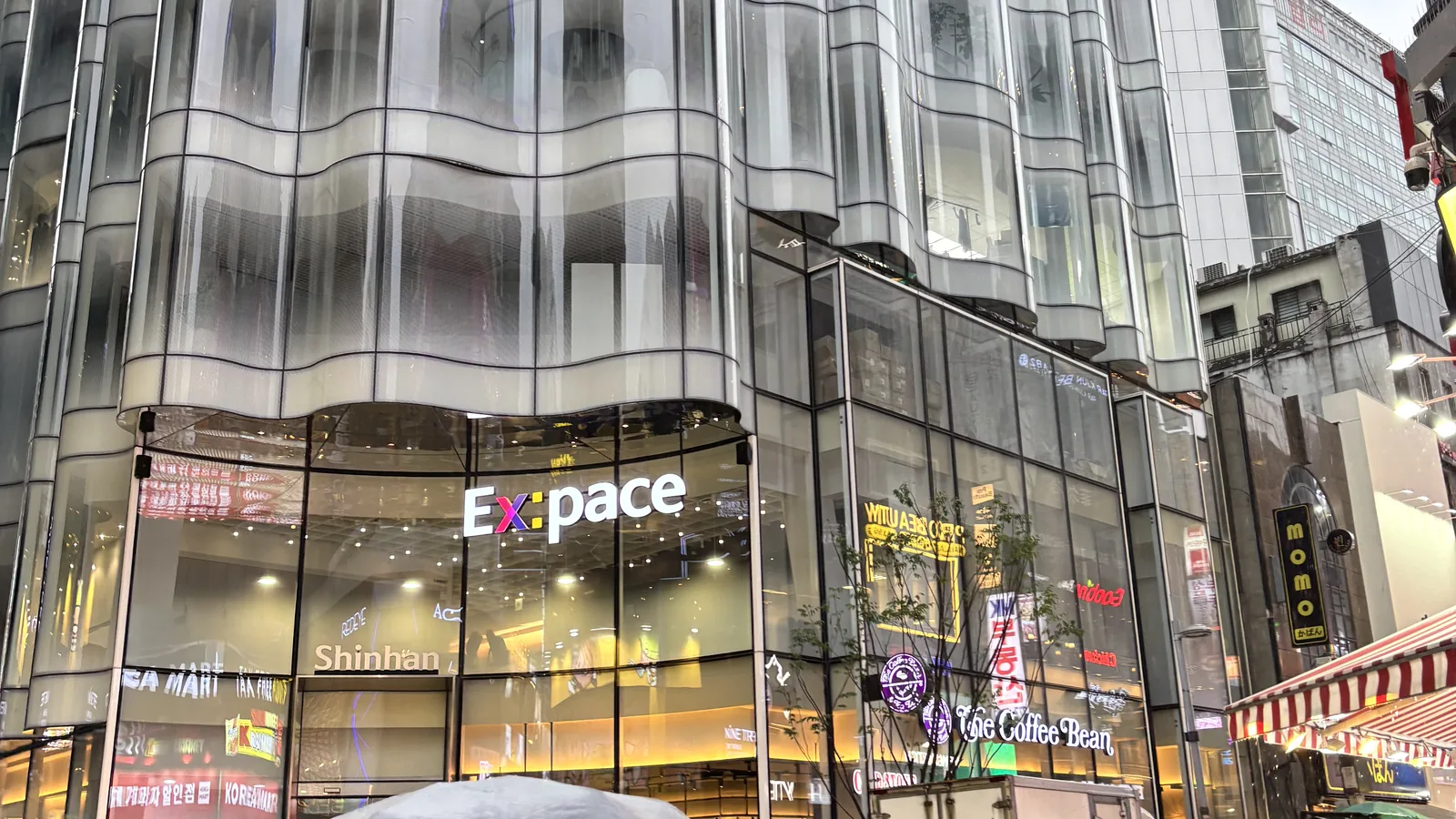 Myeongdong travel guide view of a modern glass building and bank on a quiet, rainy evening