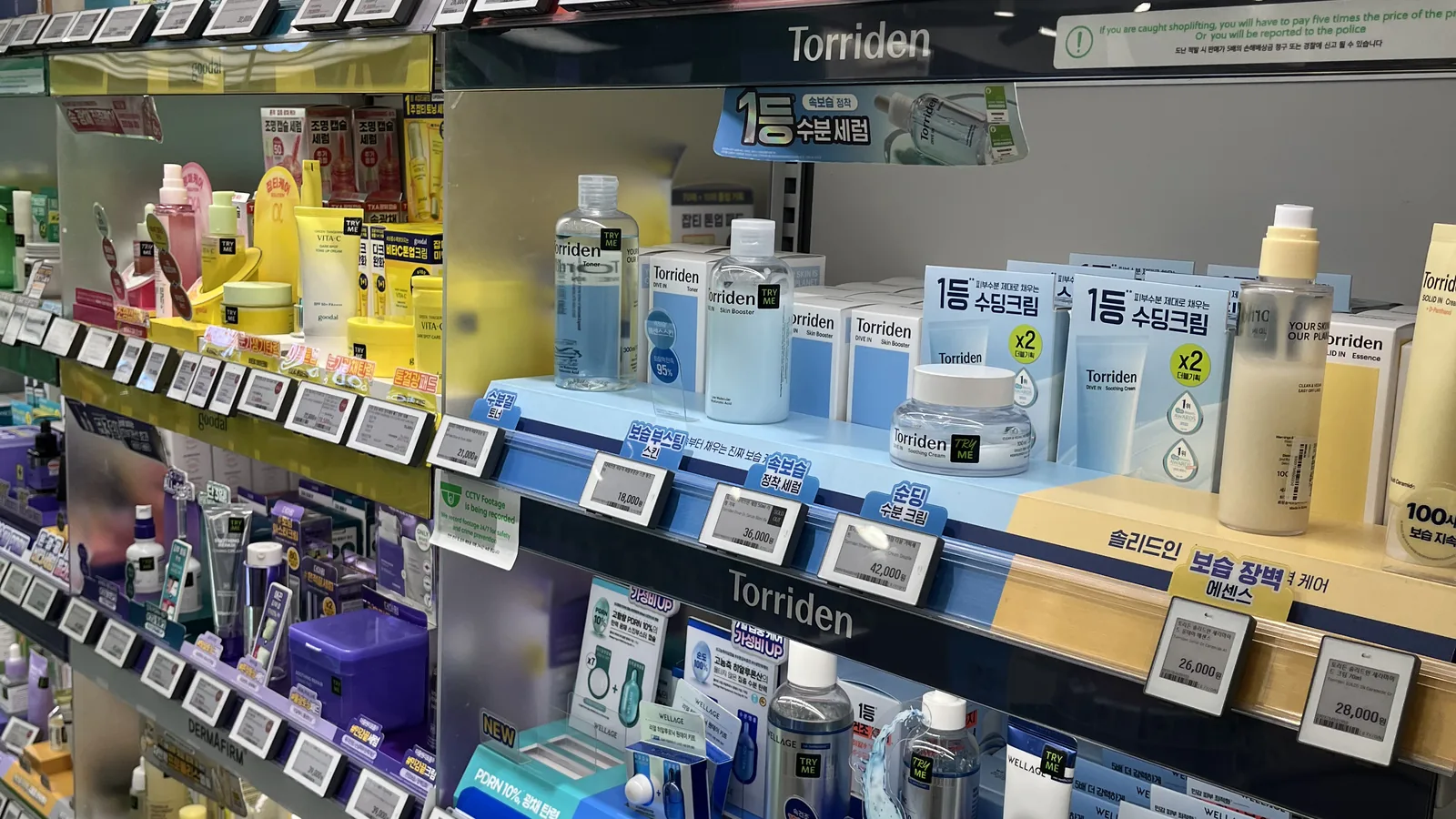 best Olive Young products lined up across a skincare wall of toners and essences in Seoul