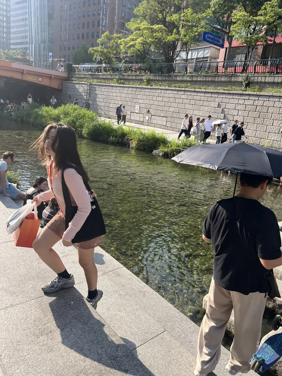 Cheonggyecheon in summer with a visitor relaxing at the water's edge on a hot day