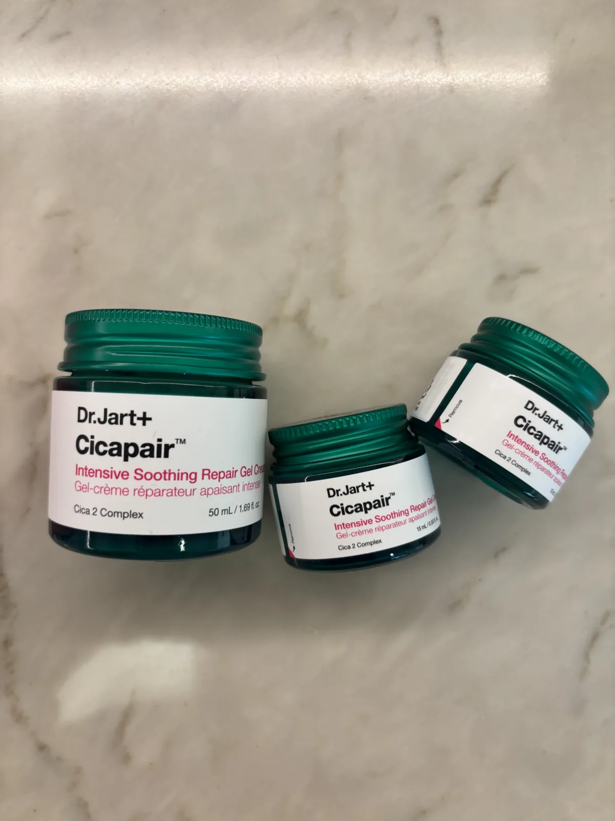 Dr.Jart Cicapair gel cream green glass jar with travel size minis on a marble surface