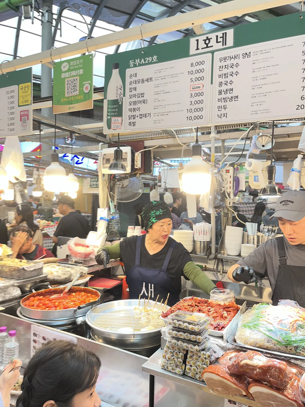 How to visit Gwangjang Market shown by a food stall with overhead menu boards