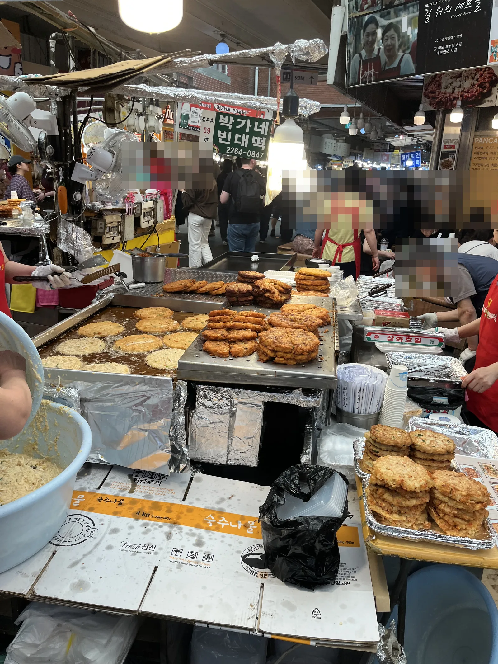 Gwangjang Market bindaetteok stall with frying pans and stacked pancakes