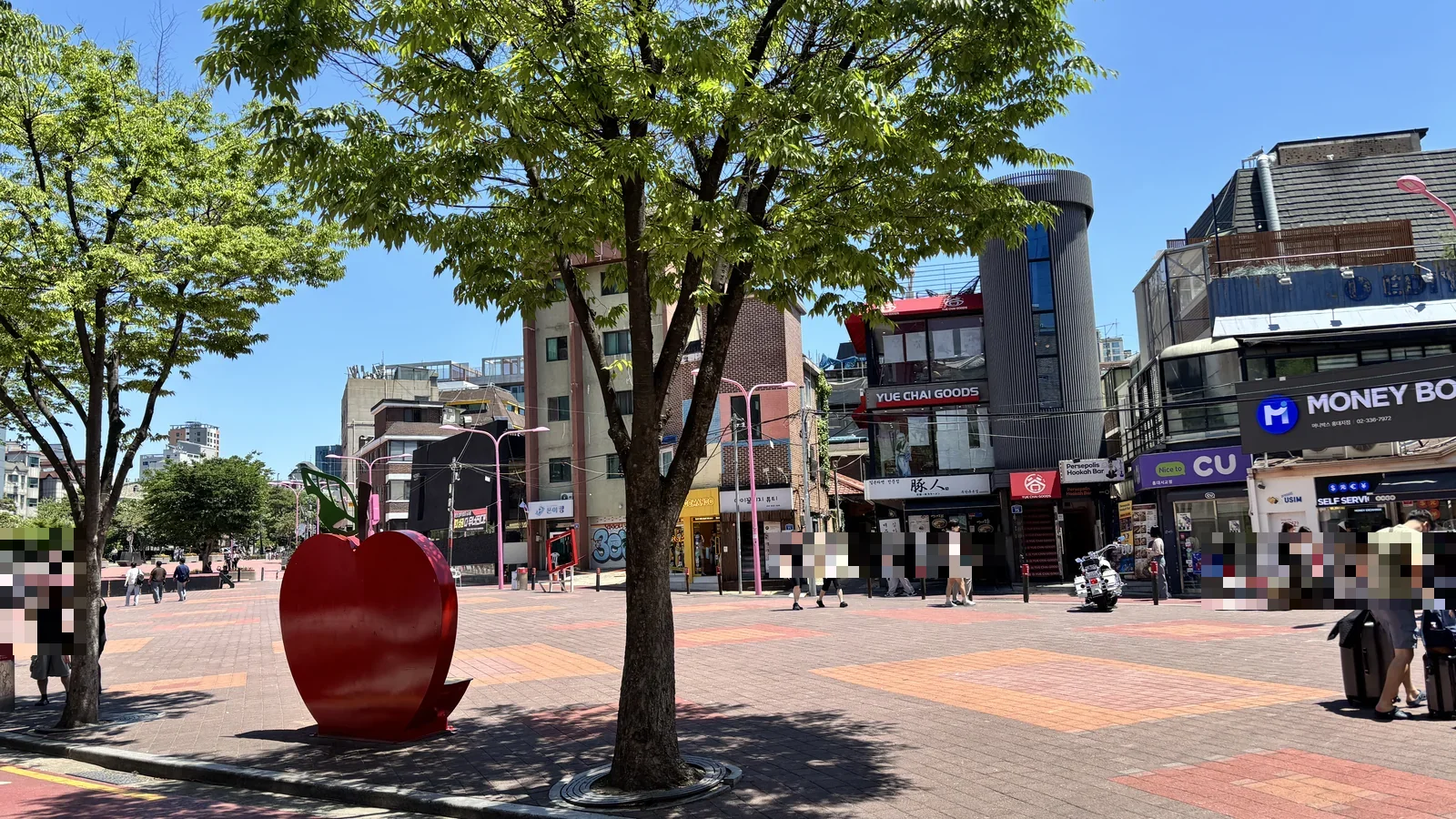 Red apple sculpture in Hongdae's pedestrian plaza lined with cafes and shops — a landmark stop in this Hongdae Seoul travel guide