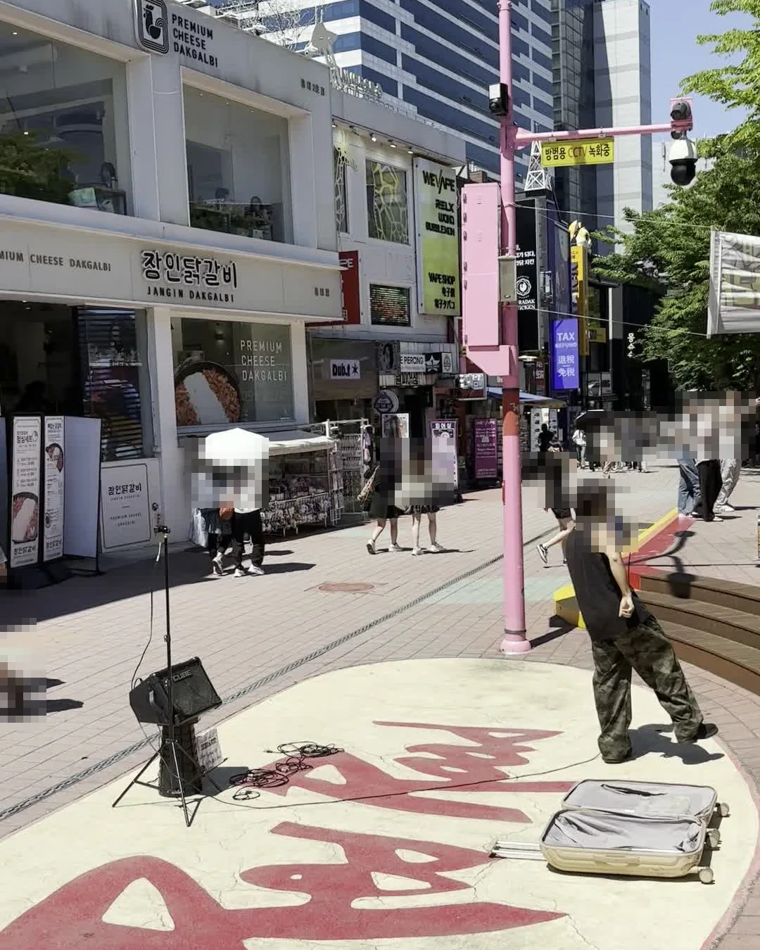 things to do in Hongdae on a weekend — street busker performing on the Red Road stage with amp, mic and an open case for tips